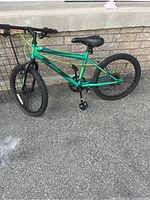 Full side view of the green Novello kids bike showing frame, tires, seat and pedals.