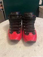 Front view of black and red Reebok men's athletic shoes showing toe and lace areas.