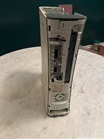 Front and bottom corner view of white Xbox 360 console showing worn and dirty exterior with some panel damage or missing parts
