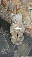 Front view of hand-carved wooden bear sculpture showing detailed carving and cracking at base.