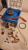 Assorted costume jewelry and bracelets along with blue jewelry box with compartments and a white decorative lid box.