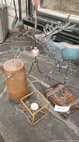 Photo of copper kettle, metal deer weather vane, and geometric candle holder on stone floor