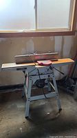 Photo of the Delta jointer showing entire machine and table, placed on a stand in workshop.
