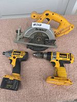 Overview photo showing the DeWalt cordless circular saw, cordless impact drill with battery, and cordless drill without battery on a carpeted surface.