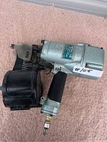 Side view of Hitachi coil nailer showing body, handle, magazine and air fitting