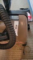 Close-up of the vacuum hose attachment to the main vacuum unit, showing model label partially visible.