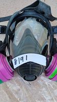 Front view of full face respirator mask showing clear visor and dual pink and green filters.