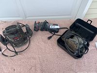 Lot photo showing all three tools arranged side by side on a carpeted surface: the Skil router on the left, RotoZip saw in the middle, and Porter-Cable palm sander in its case on the right.