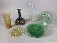 Full lot overview showing the glass liquor bottle, green plates, clear vase, amber vase, and yellow plate