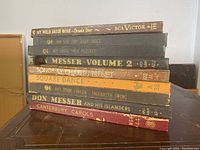 Photo showing stacked spine views of nine old 78 RPM gramophone record albums with various titles and conditions.