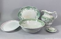 Group shot of the entire porcelain set including pitcher, platter, wash basin, dish, small container.