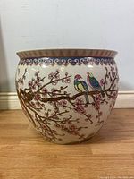 Front view of large circular porcelain planter showing colorful hand-painted birds on cherry blossom branches.