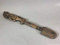 Top side view of carved wooden tribal staff showing human figure and worn wooden texture