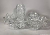 Wide shot of the vintage crystalware collection showing a tall vase, footed fruit bowl, small footed bowl, and multiple pitchers with cut glass detailing.