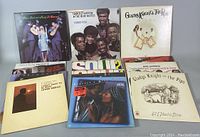 Photo showing multiple vintage vinyl albums from artists including Gladys Knight & The Pips, Harold Melvin & The Blue Notes, Peter Paul and Mary, and others. Several records arranged to show the cover art clearly.