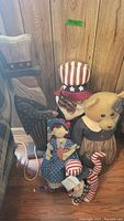 Wooden Uncle Sam, plush Uncle Sam doll, bear, cat, and small doll grouped together showing lot contents and approximate sizes.