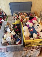 Plastic bins containing multiple Ty Beanie Babies and other plush toys of various sizes and colors.