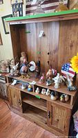 Wide shot showing collection on wooden shelf including various bird figurines, patriotic plates, and candle items.