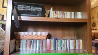 Wide view of multiple shelves containing about 70 CDs, some in stacks and some lined up, showing a variety of jewel cases and album covers.