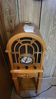 Photo of Crosley Collector's Edition Radio in wooden arched cabinet with speaker grille, dial, knobs, and stand.