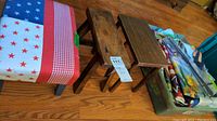 Three mini step stools and a plastic bin filled with various decorative flags, with a metal flag stand next to the bin on hardwood floor.