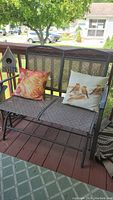 Patio glider on front deck with birdhouse decoration and two decorative pillows: one bird design, one floral design