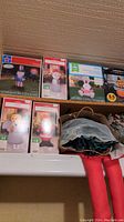 Shelf with boxed holiday inflatable decorations of various characters, including snowmen, bunny, and Santa Claus.