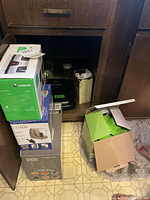 Full view of kitchen items in open cabinet, including boxed small appliances and loose kitchen tools visible