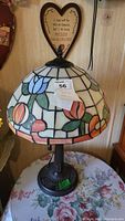 Side view of Tiffany style lamp showing colorful stained glass floral design on the shade and decorative metal base.