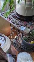 Photo showing the top and side of the vintage Singer metal sewing table base surrounded by plants and other items.
