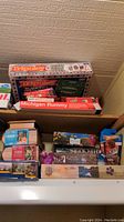 Boxes of board games and puzzles stacked including Michigan Rummy, Sorry!, and 1000-piece puzzles visible