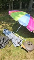 Photo showing multi-colored beach umbrella, patio umbrella fabric, brown plastic umbrella stand, and bundled plastic garden fence edging pieces.