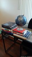Photo showing two stacks of assorted books and a world globe on a desk.