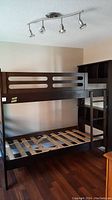 Full view of wooden bunk bed with ladder on side, headboard shelves, and mattress slats visible.