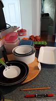 Full view of lot items including casserole dishes, fry pans, plastic lids, and lazy Susan turntable