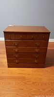 Front view of the Ethan Allen wooden chest of drawers showing six drawers with brass handles and knobs.