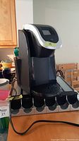 Front view of black Keurig coffee maker on top of a table showing the digital display and pod holder in front