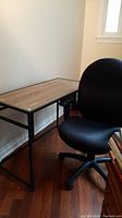 Overall view of metal framed desk and black adjustable office chair in room