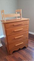 Photo of the pine wood dresser showing four drawers with wooden handles and some surface scratches.