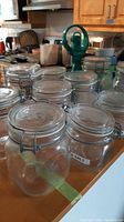 Photo showing ten clear glass Fido jars with metal snap closures on kitchen counter.