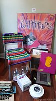 Group photo of all items arranged on floor showing colorful woven chair, cat poster, frames, game boxes and music boxes