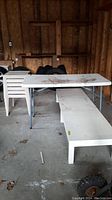 Garage setting showing stacked white garden cube tables, folding table, and coffee table