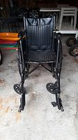 Front view of black foldable wheelchair with padded seat and footrest, showing the seat cushions and footrest configuration.