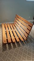 Wooden futon frame angled view showing slatted construction and wood finish.