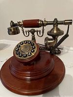 Side view of the antique replica rotary style phone showing push button dial, wooden base, and metallic handset with wood grip.