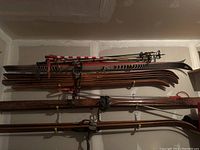 Five sets of wooden skis mounted on the wall along with one set of zebra-patterned skis and two ski poles.
