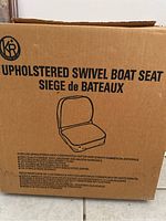 Cardboard box labeled 'Upholstered Swivel Boat Seat' with product details printed on it
