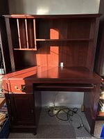 Wood computer desk with hutch, drawer, and cabinet in dark wood finish showing overall structure and storage features