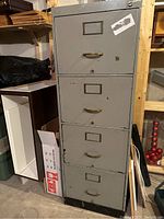 Metal 4 drawer filing cabinet showing front view with handles and label holders, scratches and chipped paint visible.