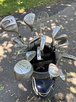 Top view of golf clubs arranged inside the golf bag, showing various irons, a putter, sand wedge, and driver heads